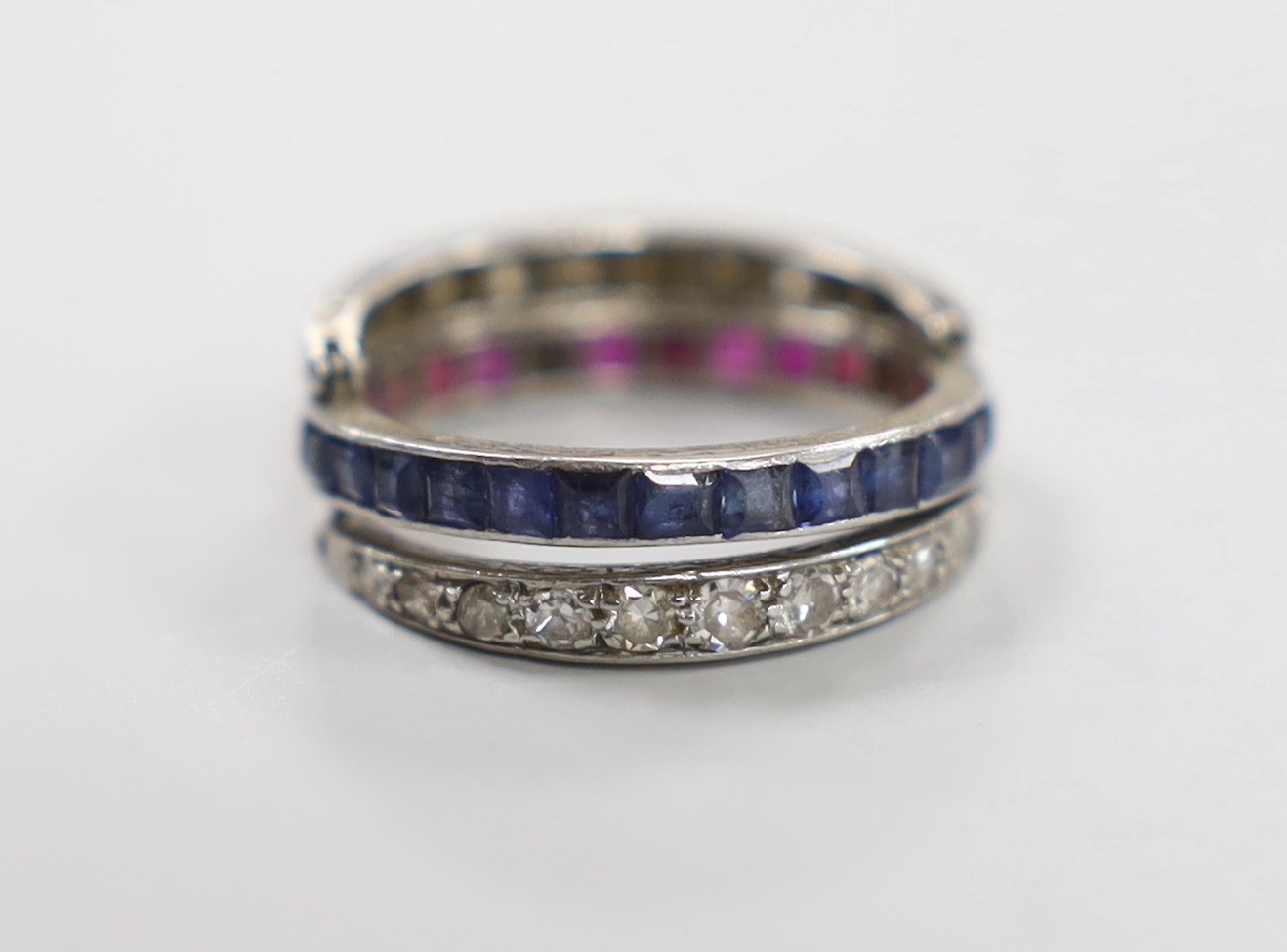 A white metal, sapphire, ruby and diamond set triple band swivel ring, size L, gross weight 4.4 grams (a.f.).